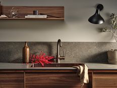 Moderne kjøkken med mørke trematerialer, integrert vask og bronsefarget kjøkkenbatteri fra Tapwell, dekorert med røde bær og minimalistiske detaljer.